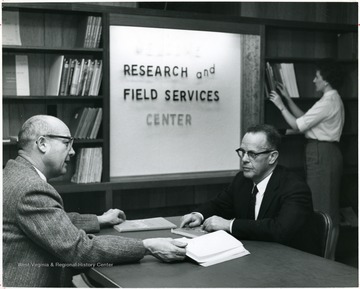 A portrait of education professors Arthur N. Hofstetter and Kermit A. Cook seated in the Research and Field Services Center of Oglebay Hall.