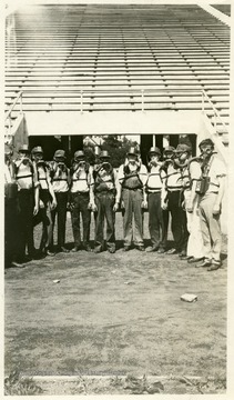 Men wearing safety gear lined up in a stadium, likely Mountaineer Field.
