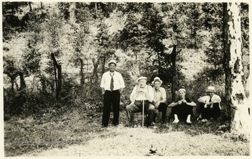 Five unidentified men gathered together in a wooded area for a portrait.