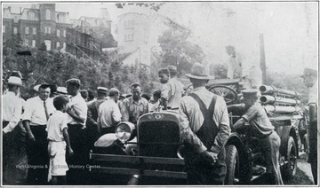 A photograph of a crowd gathered around a fire truck in Morgantown, W. Va., with Woodburn Hall in the background on the left.