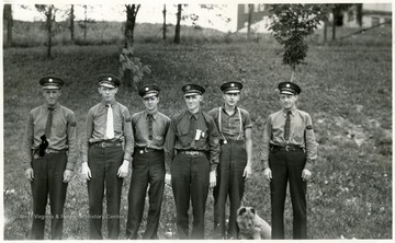 A photograph of six men in uniform. Given the left arm patch on two of the men (center and far right), it appears that they are part of a rescue or ambulance group.