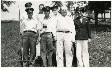 A group of unidentified men, some in uniform, standing on a hillside.