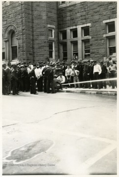 A group of people observing fire safety training outside a building.