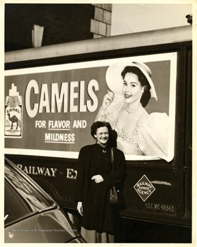 A woman pose in front of a Camel advertisement at B & O Depot.