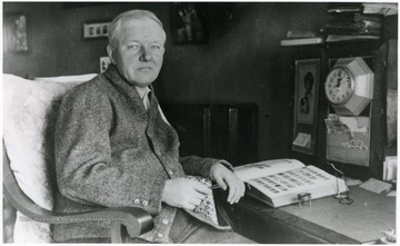 A portrait of John McDermott seated at his desk.
