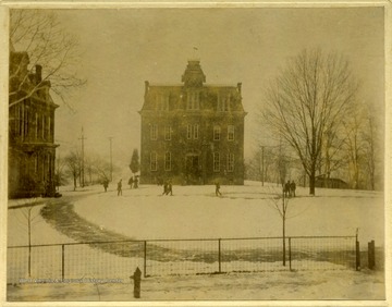 A view of Woodburn Hall and students in the circle on a snowy day.
