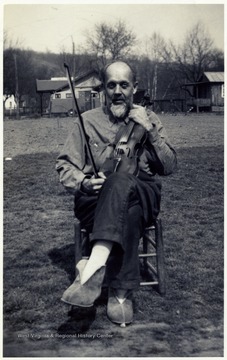 A photograph of Emerson Moore seated outside with a fiddle.