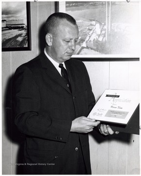 A photograph of Warren Moss posing with a certificate of appreciation.  'Later on WVU faculty.'