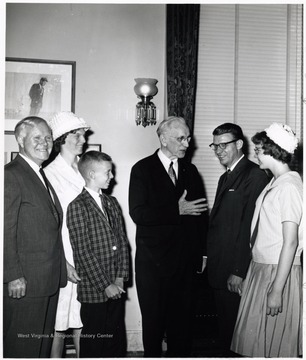 A photograph of Harley Staggers (left) standing with Speaker of the House John McCormack (center) and others.