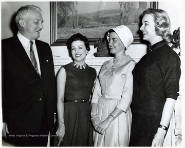 'West Virginia Cherry Blossom Princess - Miss Eleanor Cook of Holden (second from right), West Virginia's princess in the Cherry Blossom Festival, is greeted by Senator Chapman Revercomb (R-WVA) at his Washington office. Miss Cook is flanked by two of her West Virginia attendants, Mrs. Jacquelyne Blake (standing next to the Senator) and Miss Sandra Waggy of Charleston. Both Miss Waggy, who represented West Virginia in the Miss Universe Contest in 1954, and Mrs. Blake are secretaries in Revercomb's office. Miss Cook, daughter of Mrs. Henry H. Cook, Sr., of Holden, is employed as a receptionist for an insurance firm in Washington.; --From Gene Scott'