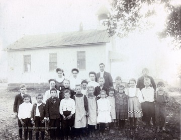A photograph of a group of children and what appears to be their instructor (center rear) outside the school building.