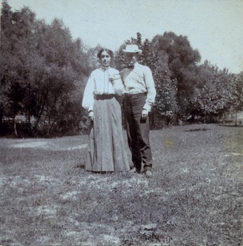 A photograph of a man and a woman (holding a horseshoe) standing together in a field.