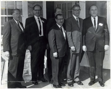 A photograph of Senator Randolph (center, back row) standing outside a building with Secretary of Agriculture Orville Freeman (second from right) and J. W. Ruby (owner of Sterling Faucet) among others.