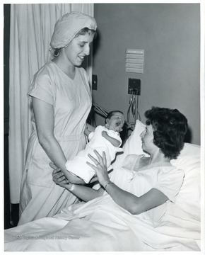 Nurse Judy Ware presents Deidra Dawn to Mrs. Robert Tucker of Smithfield, W. Va. Mrs. Tucker was the first patient to gives birth at WVU Hospital after a successful open heart surgery.