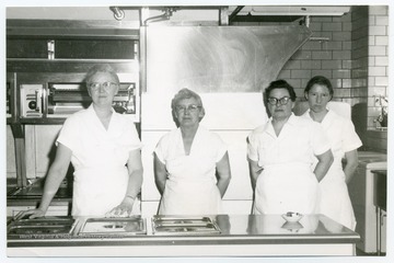 Four women in a commercial or cafeteria kitchen.