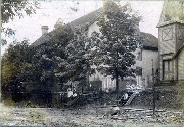 A photograph from the street of two homes, with people sitting on stairs in front.