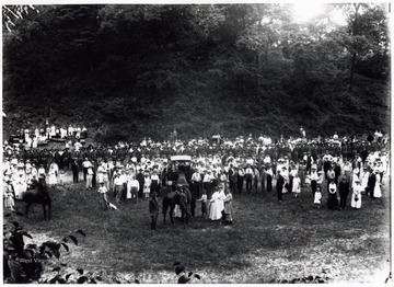 A photograph of a crowd gathered in a field to watch a demonstration by troops.