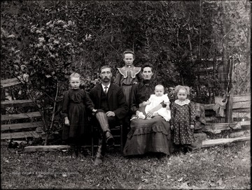 Man and woman and four children pose for portrait outdoors.
