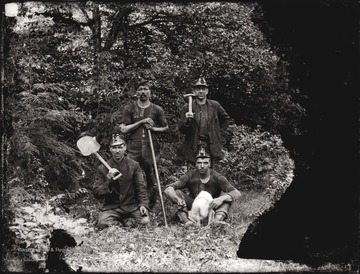 A portrait of four miners with mining tools, taken outdoors.