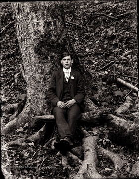 A man sitting at the bottom of a tree.