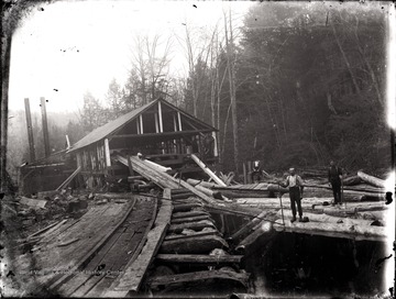 A view of lumber mill, rails leading toward it and loggers on the site, Helvetia, W. Va.