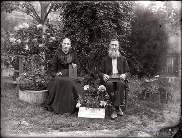 A portrait of an old couple seated in the garden clutching books, Helvetia, W. Va.