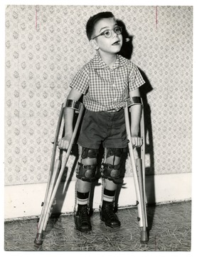 An unidentified boy fitted with braces and crutches.