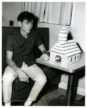 An unidentified man sits by a scale model of church.