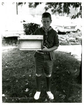 An unidentified scout holds a bird feeder in his hands.