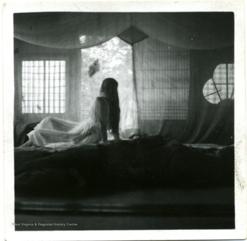 An unidentified woman sitting behind the mosquito nets.