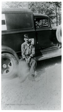 A portrait of Crane Weaver sitting on a footstep of truck; CCC 32.