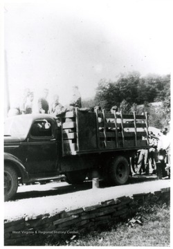 Men board onto the bed of transportation truck.