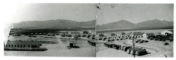 A view of camp, the headquarters, tents and work vehicles are shown.