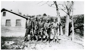 Five males pose with rifles and rabbits they caught in Morgantown, W. Va.