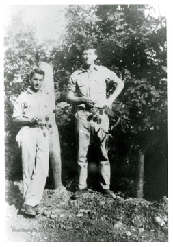 Two males holding branches with prickly chestnuts.