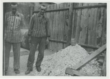 Male prisoners of Buchenwald standing by a rock pile.