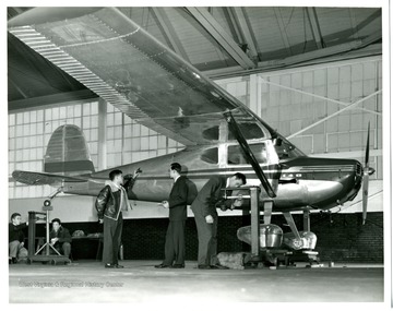 Students working on an airplane in a hanger.