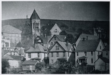 This is written on the back of the photo: 'At far left is part of porch of the old WVU President's home. Also part of the old Commencement Hall (or Reynolds Hall), and in middle is Administration Building. On crest of distant hill is old WVU observatory(built 1900, burned 3 Nov. 1919). This stood at site of present Pi Kappa Alhpa Fraternity on north High Street near Belmont Avenue. On far right in picture is visible steeple of the old Lutheran Church (torn down recently to make way for the new chapel). From old glass place negative in WVU Library. 12 Jan. 1970 '