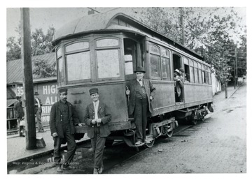 Two operators and a gentleman pose with a parked street car.