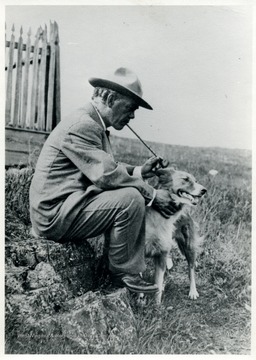 A portrait of John Strother, son of David Hunter Strother, with a long stem pipe on his hand petting his dog.  
