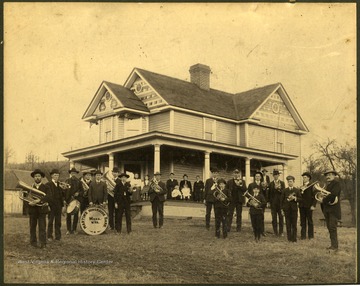 Ella Stoneking Wells 1st on porch beside little girl with plaid dress. Musician to the far right is Taylor Martin. Third Musician right, from the open space is George Wells'.