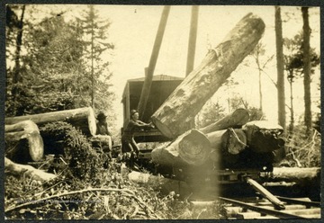 Unidentified worker guides huge log onto a rail car.