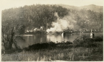 'Bridge across New River, lumber passed over this bridge from mill and was piled of yard on opposite side. Trucks were moved by power line from mill.'