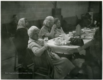 Woman facing camera is the oldest person at the dinner.