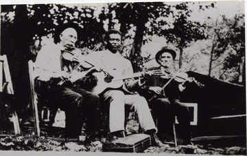 Three musicians seated next to each other playing instruments. From left to right: Dan Friend (?), Grafton Lacey (?), Jack McElwain.