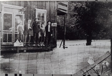 Portrait of a group standing on the ledge of a storefront as flood water surrounds them.