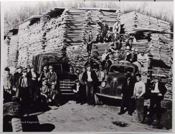 Large group posed with cars and large stacks of lumber. A portrait of a "log job close to Jerryville on Gauley River".