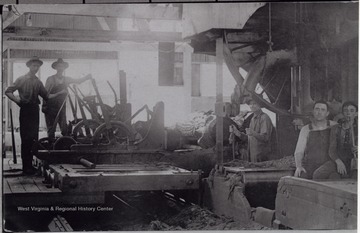 Portrait of mill workers posing around the mill equipment.