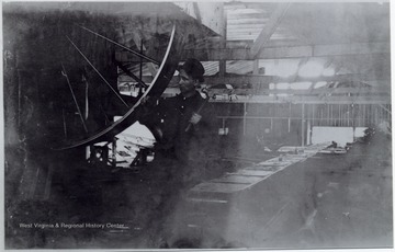 Mill worker posed next to a large wheel with a hammer in his hand.