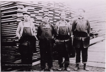 Group of workers posed in front of lumber stacks.